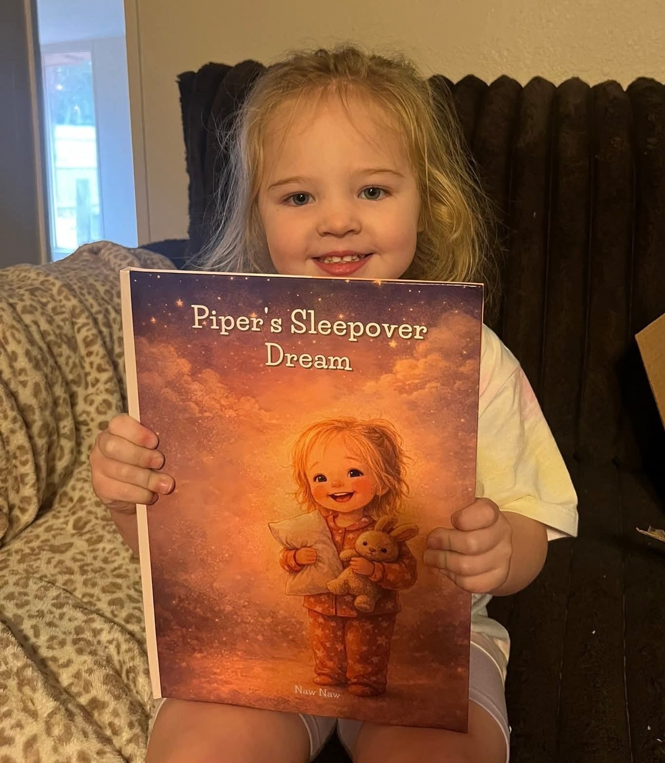 Smiling child holding a personalized sleepover storybook.